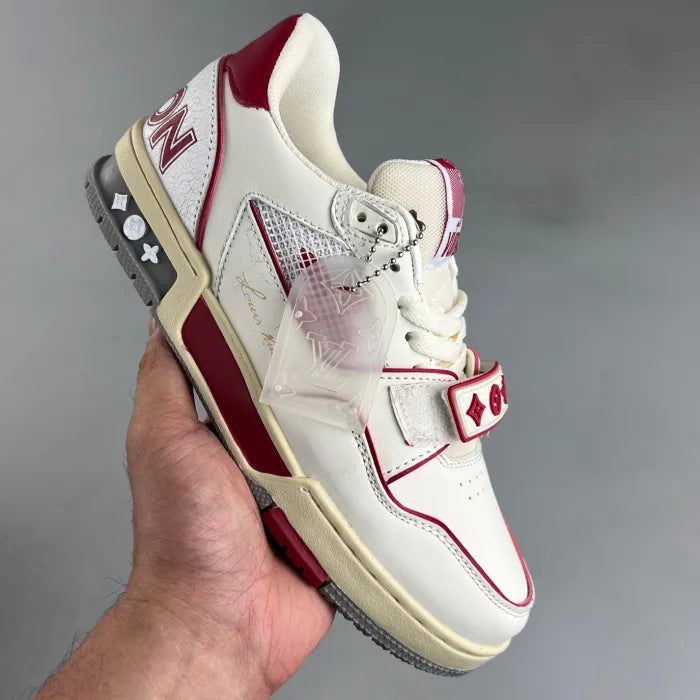 Tênis LV Trainer branco violeta segurado na mão com detalhes em vermelho e cinza